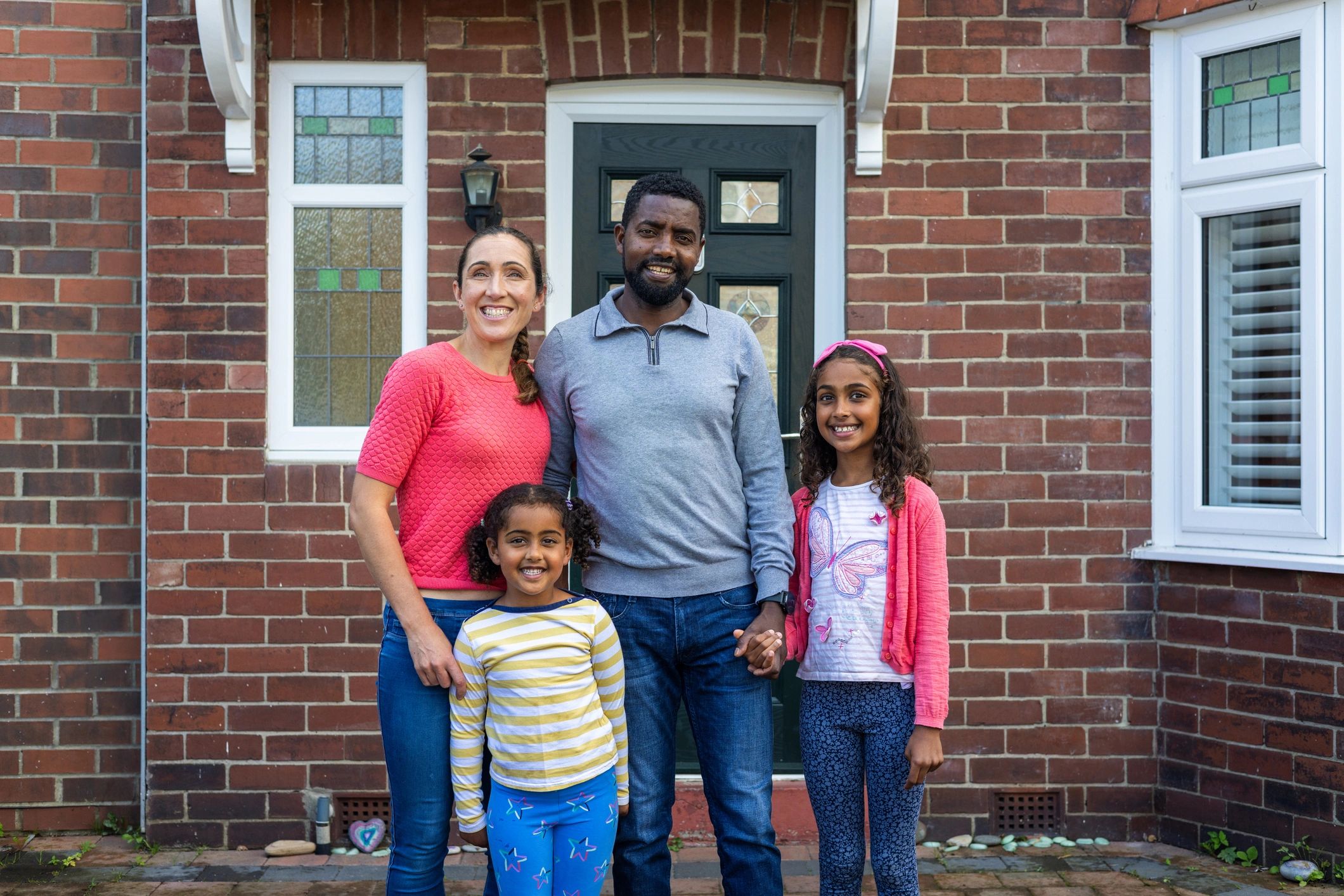 Family standing proudly outside their home